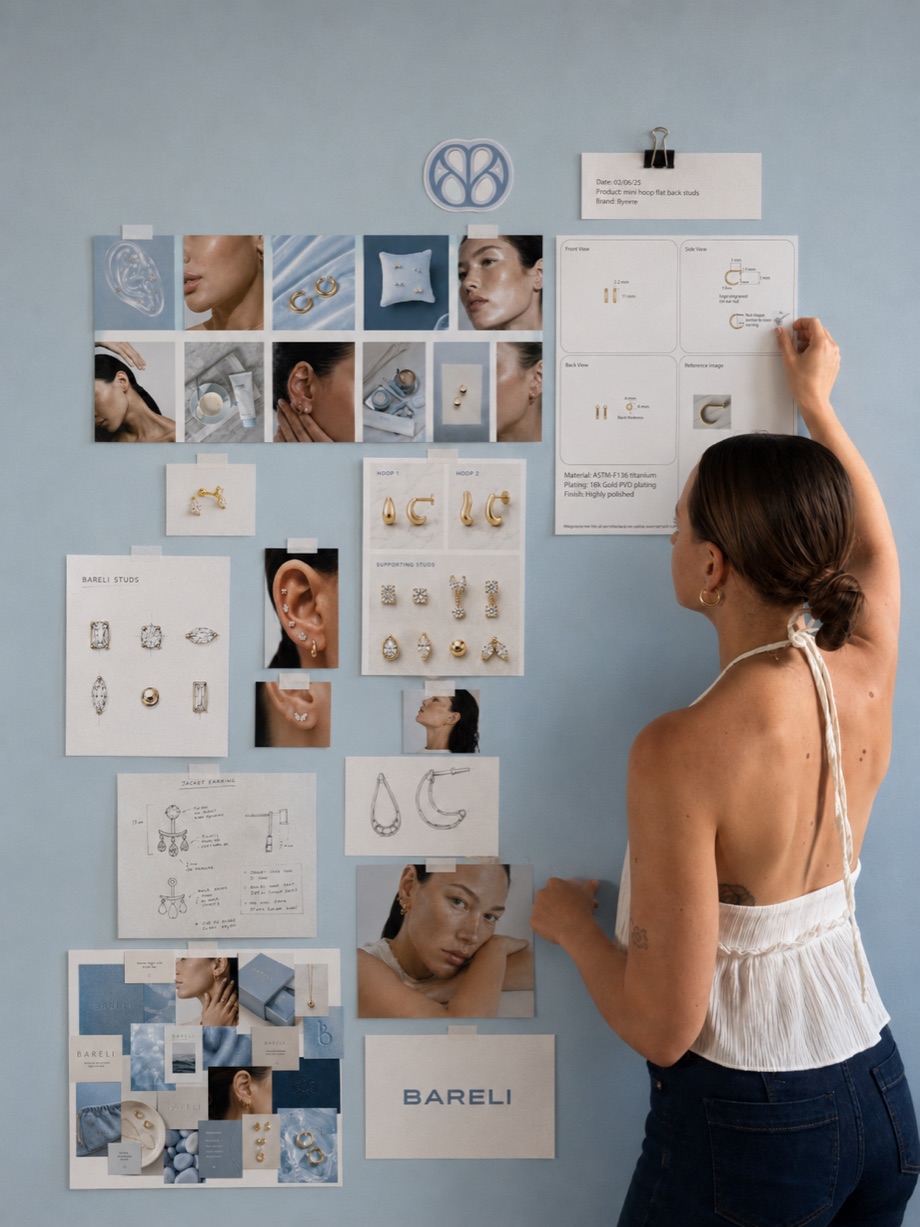 Jasmin arranging Bareli design sketches and product photos on a studio wall